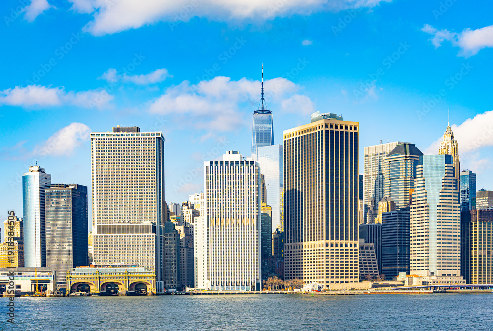 Obraz premium Panoramic view of Lower Manhattan skyline in New York City with One World Trade Center and modern skyscrapers seen from the East River on a sunny day