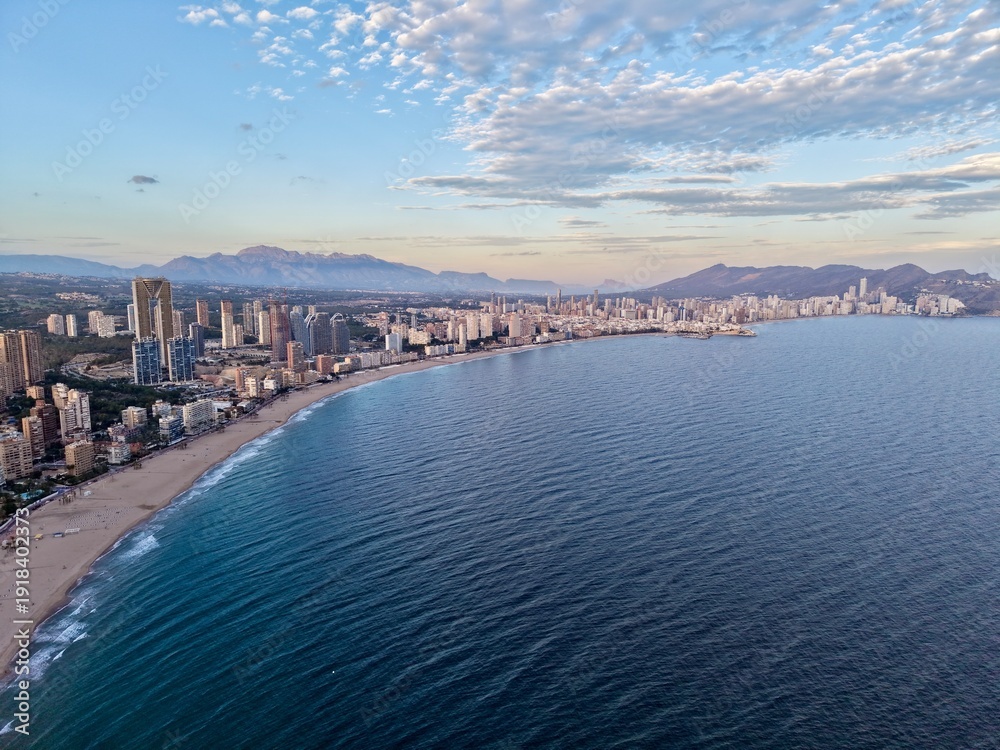 Fototapeta premium coastline sea panorama, vast coastal waters and city edge form picturesque curve under gentle morning light