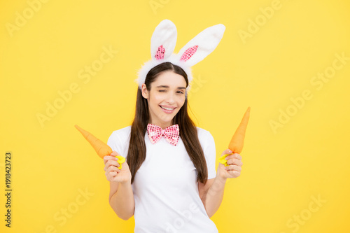Funny woman with bunny ears celebrate easter on yellow studio background. Bunny girl face. Woman in easter rabbit mask.