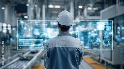 asian male engineer in yellow hard hat monitoring smart factory, automation control system with holographic data interface in manufacturing plant, industrial engineer using futuristic digital twin