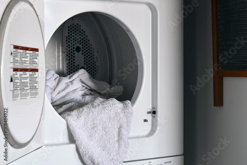 Cuadro en lienzo Open door of a household clothes dryer revealing white wet towel inside the drum