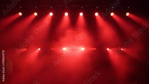 Bright red stage lights illuminate a smoky concert background