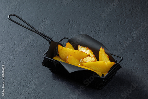 Seasoned potato wedges in black basket