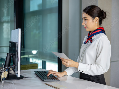 Wallpaper Mural Professional Airline check-in counter staff looking monitor and holding document at check-in desk in airport, corporate administration, customer service concept Torontodigital.ca