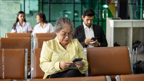 Wallpaper Mural Senior woman using smartphone and holding boarding pass while waiting at airport terminal, travel passenger concept, digital check in, modern air transportation, retirement lifestyle Torontodigital.ca