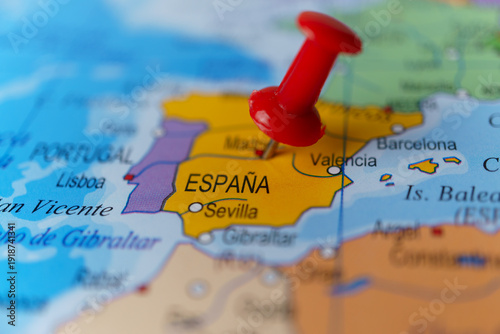 Red pushpin pointing to spain on a political world map, highlighting madrid and the iberian peninsula as a travel destination