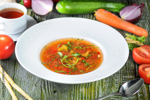 Fresh Tomato Soup with Herbs and Vegetables on a Rustic Wooden Table