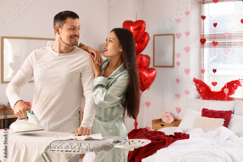 Young couple ironing clothe...