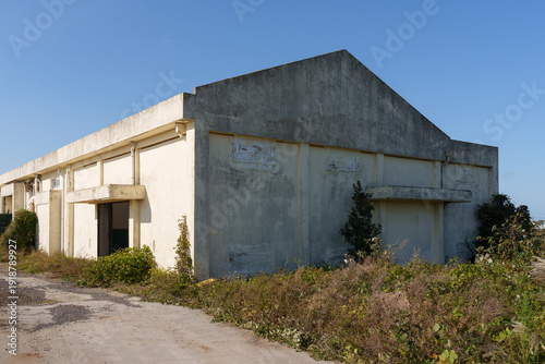 Obraz na płótnie Abandoned Industrial Building with Overgrown Vegetation