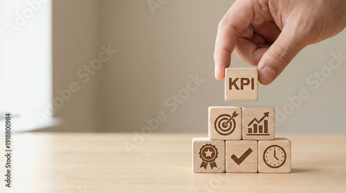 Hand placing kpi block on business strategy cubes with icons for goals metrics and performance on a wooden desk in a modern office