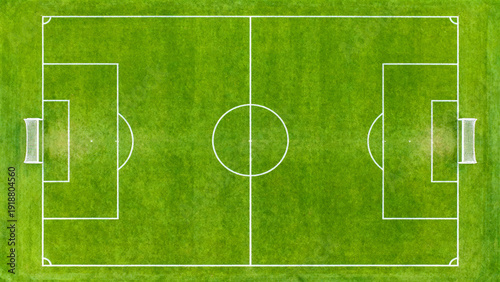 an aerial view of a rectangular soccer field with a vibrant green grass surface. The field is symmetrically divided by a white center line,