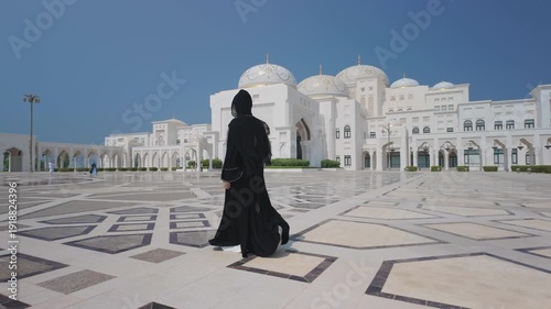 ABU DHABI, United Arab Emirates . 07.07.2025. Qasr Al-Watan Presidential Palace in Abu Dhabi .A girl in a black abaya walks along the front of the palace square.