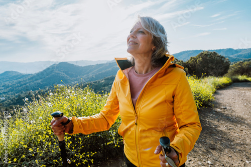 Active senior woman hiking on outdoor trail using trekking poles