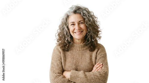 Smiling woman with curly hair wearing a light brown sweater crossing her arms in a bright setting no background