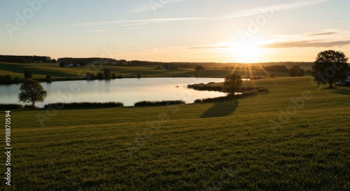Serene sunset over a green field and calm lake
