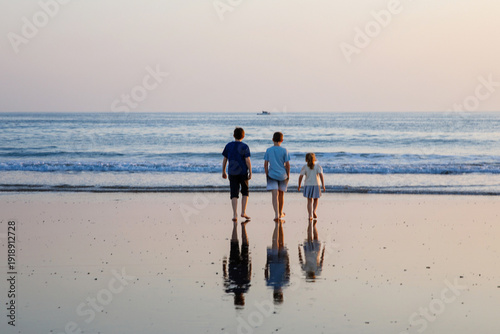 Tableau sur toile Three children, happy siblings on ocean beach at sunset