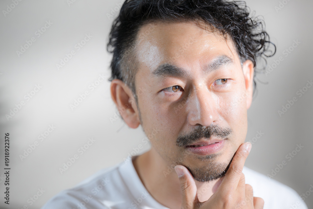 Obraz premium 髭のある ハンサムな中年男性の脱毛や顎髭のイメージ 顎を触るスキンケアなどのクローズアップの悩む考えるポーズ