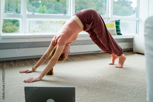 Woman practicing yoga stretching exercise indoors by window