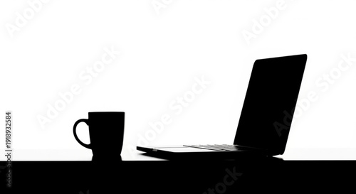 A laptop and a cup on a table viewed from the side in a modern office setting