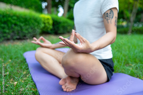 Beautiful young woman practicing Padmasana on yoga mat outdoors, space for text.