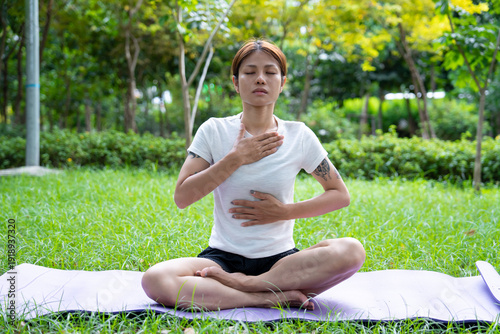 Beautiful young woman practicing Padmasana on yoga mat outdoors, space for text.