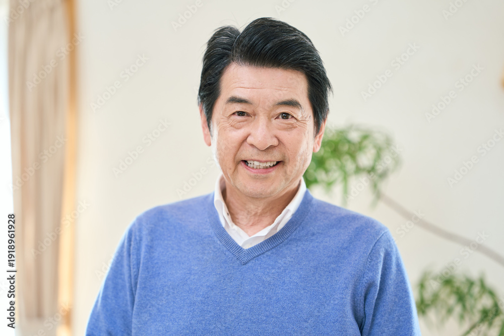 Obraz premium 部屋で笑顔で立つアジア人シニア男性