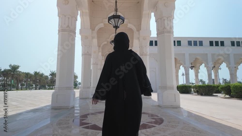 ABU DHABI, United Arab Emirates . 07.07.2025. Qasr Al-Watan Presidential Palace in Abu Dhabi .A girl in a black abaya walks along the front of the palace square.