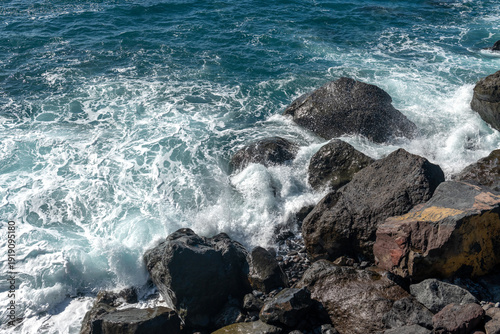 Skaliste wybrzeże oceanu z rozbijającymi się falami pod błękitnym niebem