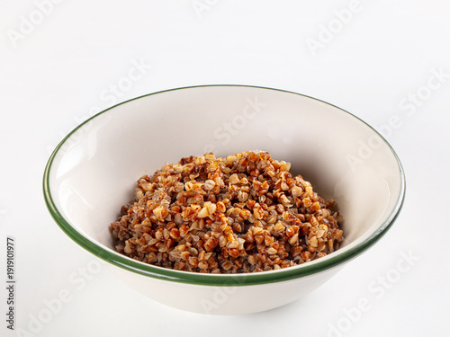 Foto Cooked buckwheat porridge in a white bowl with a green rim, isolated on a white