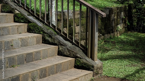 Fotografie Stone stairs with a metal handrail leading through a lush garden