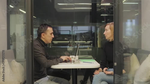 Middle aged recruiter interviewing female candidate in private office booth