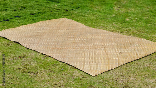 Wallpaper Mural Woven palm leaf mat laid out on lush green grass, perfect for outdoor relaxation and cultural events Torontodigital.ca