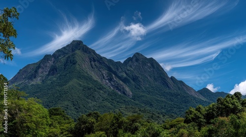 Majestic mountain peak under a bright blue sky with wispy clouds