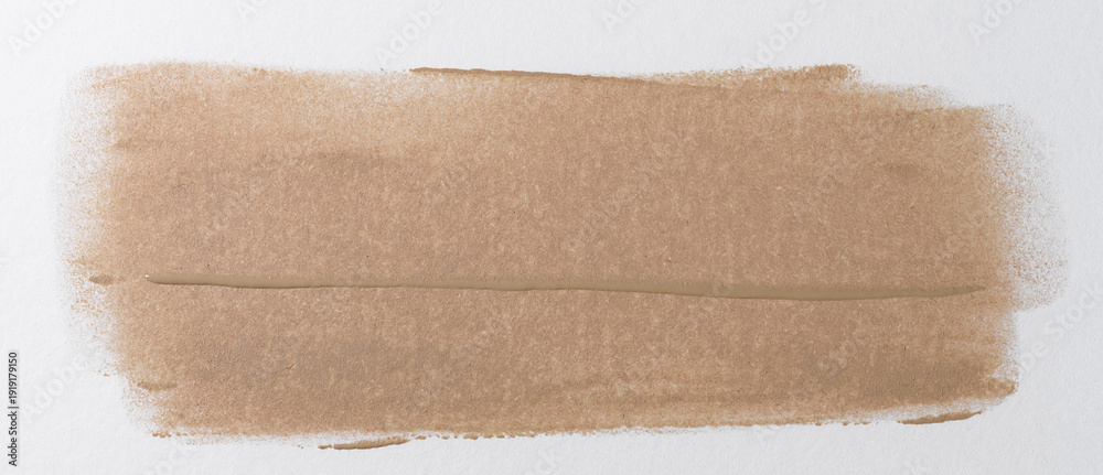 Fototapeta premium Broad brushstroke of nude or beige foundation with a distinct wave texture from the brush, glossy finish, close-up on a white background