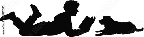 Boy reading book with dog lying beside him silhouette