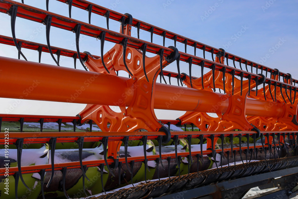 Ταπετσαρία A detailed close-up of a bright orange combine harvester header showcases the complex design of metal teeth and mechanisms