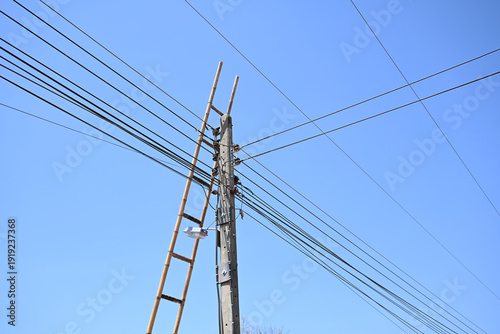 Utility pole electric wire wooden ladder blue sky power line cable network construction tool outdoor structure maintenance work minimal scene utility pole and electric wire with wooden ladder