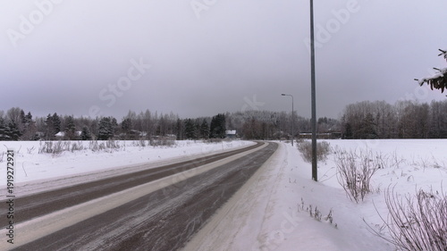 Snowy roadside with utility poles and forest in winter conditions.