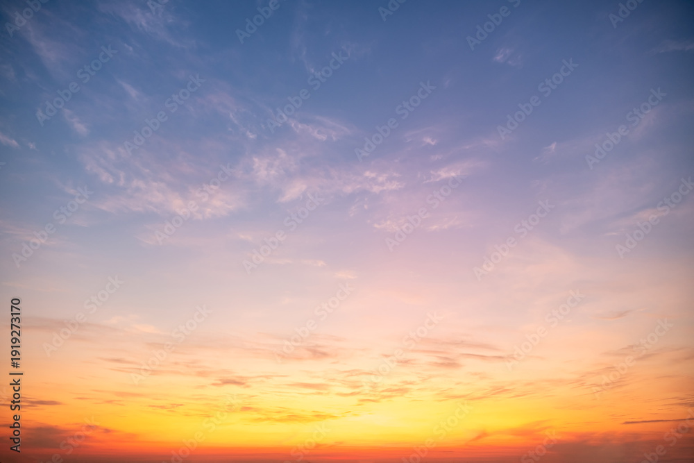 Fototapeta premium Beautiful sunrise sky with vibrant gradient orange and gold colors and soft blue, Clear atmosphere with wispy clouds. Peaceful, perfect for background and copy space, High resolution images