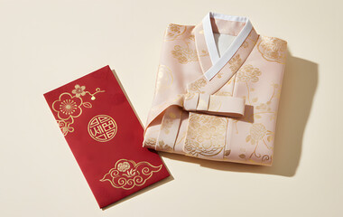 Traditional Korean pink hanbok dress and red wedding envelope with gold patterns on neutral background for celebration and ceremony
