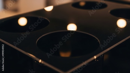 Dark, reflective surface with circular holes, lights mirroring