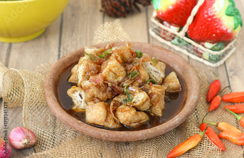 Foto An Indonesian street snack, tahu gejrot, combines fried tofu with a sweet and spicy sauce made from palm sugar, red shallots, and fiery green bird’s eye chilies