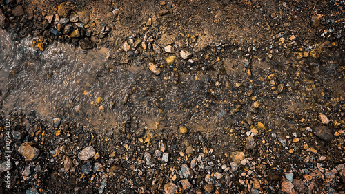 Bild auf Leinwand Overhead shot of a textured path with gravel and flowing water, rustic natural b