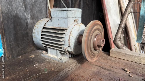 Old electric motor with spinning metal grinding wheel in workshop