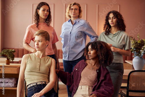 Group of diverse women in a cafe posing together for a lifestyle portrait. All the women are dressed in light pastels