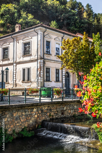 Beautiful city landscape scenery of Florina Greece, river canal and trees around, flowers in the foreground, historic buildings and neighborhood, Arcturos brown bear shelter
