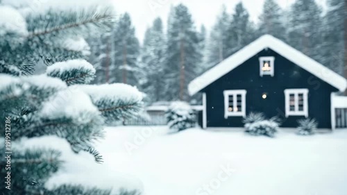 Snow falls gently on a dark cabin in a winter landscape filled with trees and a lively snowfall. A small light glows inside