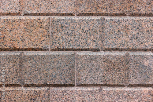 Εκτύπωση καμβά A close-up view of a red gray, speckled granite block wall with beveled joints and rough texture