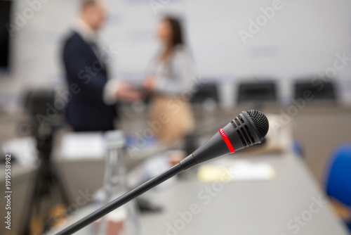 Conference microphone in focus with blurred delegates during diplomatic negotiations and official meeting.