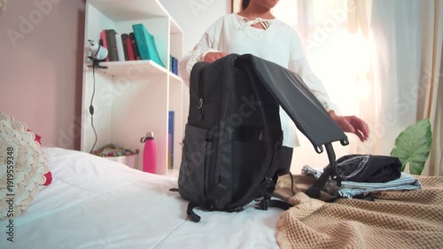 Video of a young woman in her room packing her backpack with clothes to leave home